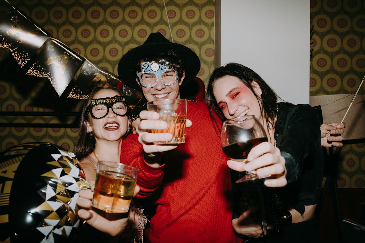 Joyful group of friends celebrating New Year's Eve with drinks and laughter indoors.